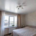 Спальня с видом на частные дома: мягкий отлив сатина у люстры